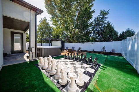 Checkmate under the sun: An expansive backyard chessboard awaits your next move, alongside a soothing hot tub for post-game relaxation