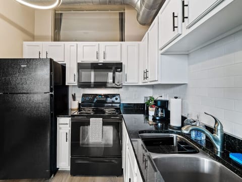 Fully equipped kitchen with black appliances and sleek granite countertops   - White cabinets and subway tile backsplash enhance the modern design   - Cook your favorite meals with ease using the stove, microwave, and coffee maker