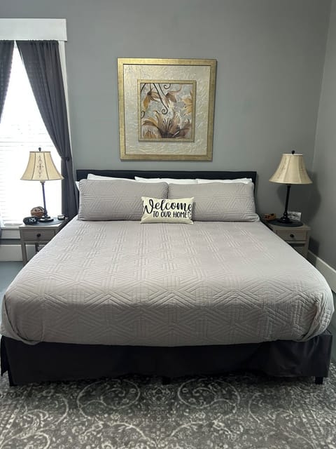 King size bed in large bedroom with custom made blinds and a ROKU TV.