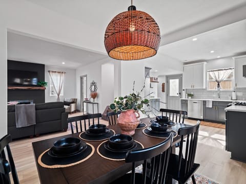 Open concept kitchen and dining with pendant lighting - Rustic wooden table set with black dinnerware style - Seamless flow to living room for easy gatherings