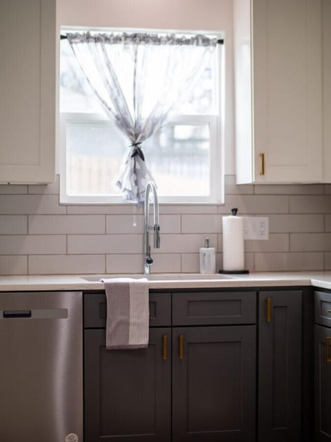 Kitchen sink with modern faucet and subway tile wall - Window with sheer curtain brings in natural daylight - Functional and bright corner for daily use