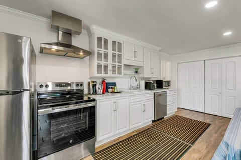 Full kitchen with new stainless steel appliances. Appliances include a refrigerator, electric stove and oven with hood, sink, dishwasher, microwave, Keurig coffee machine, hot water kettle, and air fryer. 