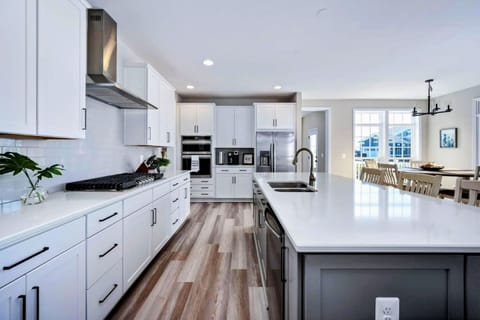 Experience culinary bliss in the generously-sized, fully stocked kitchen featuring a massive island, gleaming stainless steel appliances, and a convenient pantry.