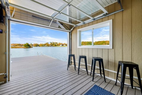 A serene lakeside space with a bar area and a fully retractable glass door that opens directly onto a spacious dock