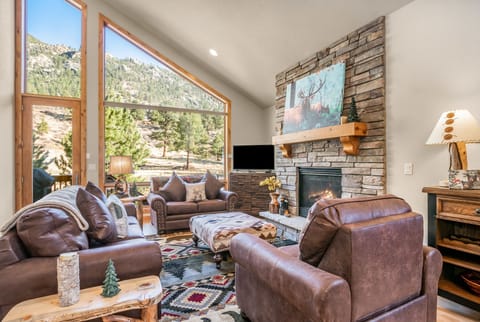 River Rock Retreat -- EV #6032 - a SkyRun RMNP Property - River Rock Retreat - Main floor living room with ample sofa seating, gas fireplace, and a serene view out to the deck. Townhome is adorned with charming mountain decor.