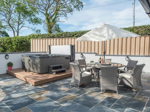 Hot tub, patio table, chairs and umbrella in the garden