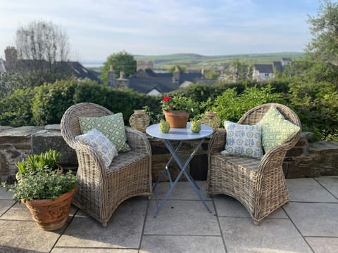 Two wicker chairs and bistro table with distant sea views