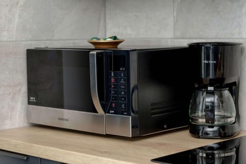 A neatly arranged microwave and coffee machine on a wooden countertop in a sleek, modern kitchen.
