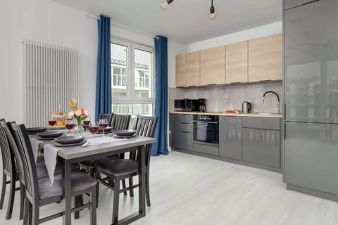 A modern dining area with a sleek table set for a meal, accompanied by wine glasses and fresh fruit.