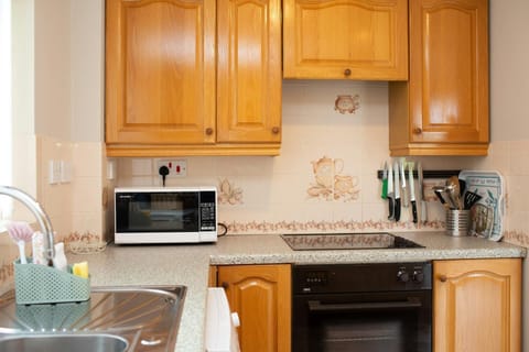 wooden cabinets and cupboard, oven, hob, microwave and utensils. magnetic knife rack