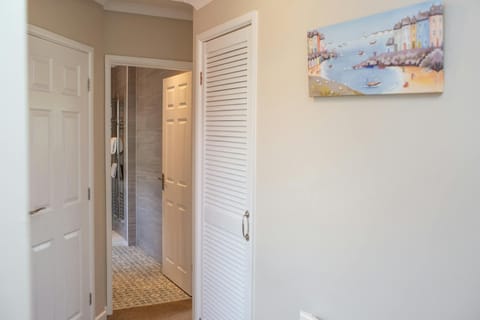 hallway leading to bathroom with wall art on wall of a seaside village