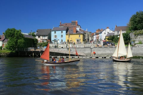 Boats and yachts on the river in Cardigan with shops and restaurants in the background