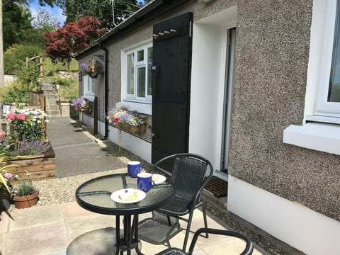 outdoor patio area with seating and flowers in hanging baskets and window box.