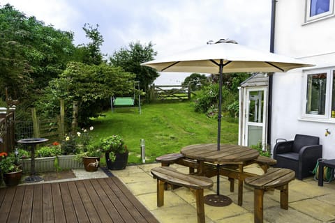 Patio area with table, seating, parasol. lawned garden and flowers