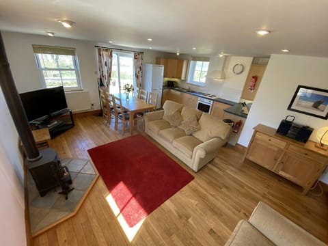 Open plan, living / dining / kitchen with patio doors, TV and logburning stove