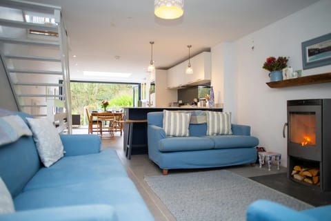 Two sofas and wood burner in the living room leading to the kitchen