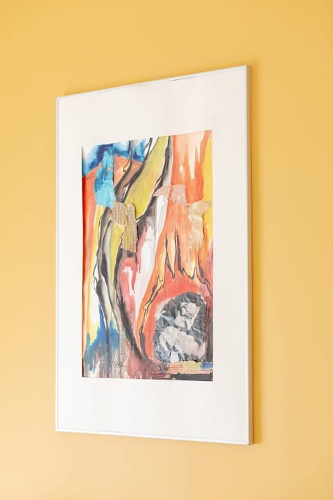 A close-up of a colorful abstract painting hanging on the yellow wall in the bedroom, adding a pop of artistic flair to the space.