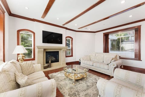 Experience the ultimate in luxury living in Vancouver with a beautifully designed living room featuring Versace sofas and a stunning TV setup.