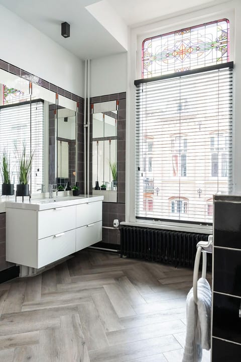 Bright, spacious bathroom featuring large mirrors and a clean, modern design, complete with a large window providing natural light.