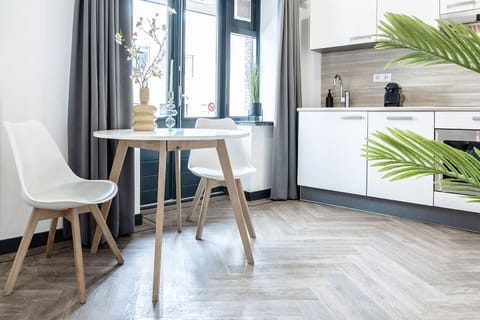 Enjoy a spacious living area with a comfortable sofa, chic pillows, and a sleek kitchen, where plants bring nature inside, offering a cozy retreat after visiting Efteling or Safari Park Beekse Bergen.