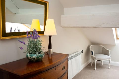 Chest of Drawers with mirror over and a vase of flowers and lamp on top.