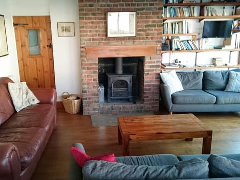 Sitting area with woodburner, two sofas, tv and coffee table