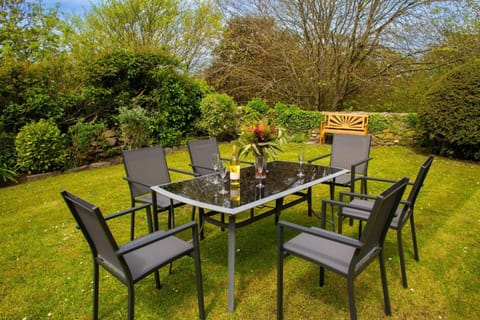 Garden table and chairs surrounded by a lawn and mature flower beds
