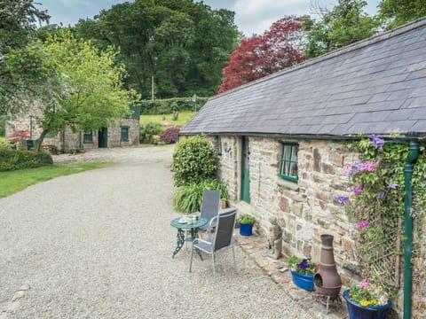 Cottage with gravel patio area with small table and chairs, surrounding trees