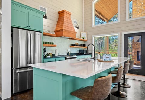 Gather around the spacious island with plush seating, accented by a pop of teal and copper fixtures that add a touch of warmth.