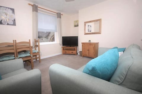 Main living room with a 3 seater sofa, cosy arm chair, TV and dimming table.