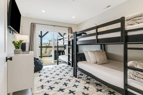 Corner view of Bedroom 5 downstairs with 4 twin bunk beds, large closet space, Smart Roku TV, and dresser