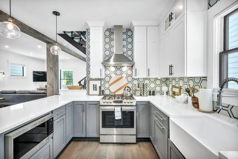 Experience the sleek design of our fully equipped kitchen, featuring stainless steel appliances, ample counter space, and a chic hexagonal tile backsplash. Perfect for preparing meals and making lasting memories.