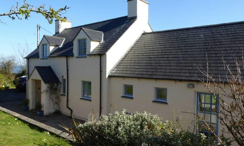 Front of cottage with porch, lawn, gravel area