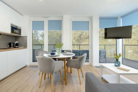  A modern kitchen with white cabinets, high quality domestic appliances and plants on the counter. The kitchen looks out onto a scenic view.