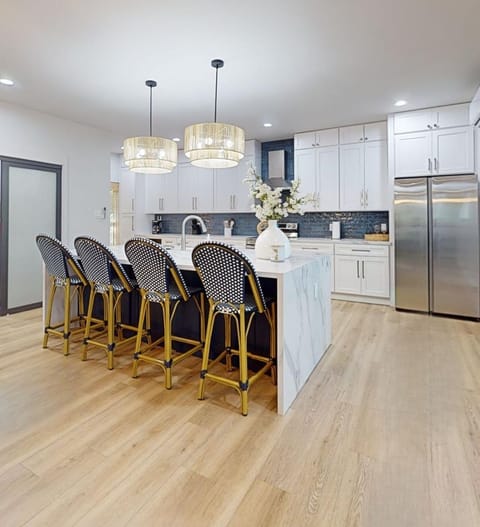 Impressive chef’s kitchen with a 6-foot quartz waterfall island, farmhouse sink, built-in wine fridge, and hidden trash storage. The island comfortably seats 4–6 and opens seamlessly to the dining and living areas—ideal for entertaining.