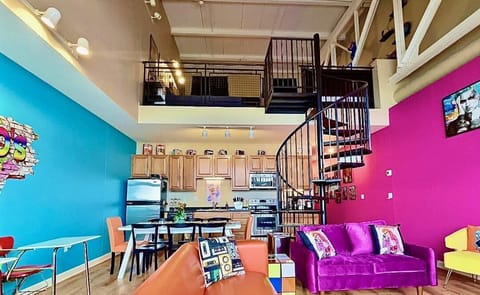 A vibrant, retro-inspired loft with a spiral staircase, bold decor, and open-concept design for a unique stay!