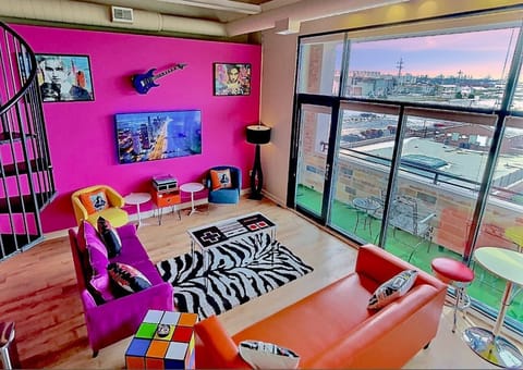 Enjoy retro entertainment with our plasma 65" TV and classic record player. This setup offers a nostalgic experience, perfect for watching your favorite shows or listening to timeless vinyl records, all in a vibrant 80s-themed setting.