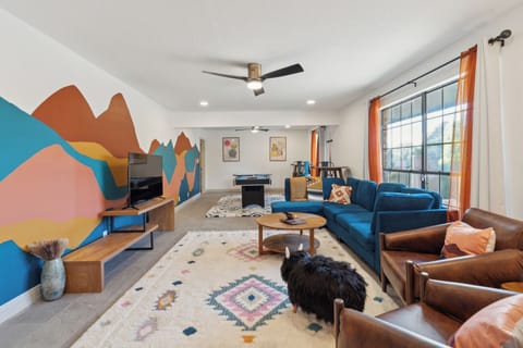 Living room with eclectic couches, ceiling fan, and windows with curtains