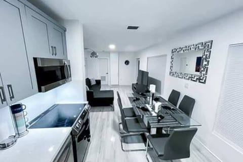 Sleek, modern kitchen with stainless steel appliances, ample cabinet space, and a glass dining table for six. Perfectly equipped for cooking and dining, offering a stylish and functional space for your stay. Ideal for comfort and convenience.