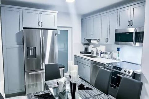 Sleek, modern kitchen with stainless steel appliances, ample cabinet space, and a glass dining table for six. Perfectly equipped for cooking and dining, offering a stylish and functional space for your stay. Ideal for comfort and convenience.