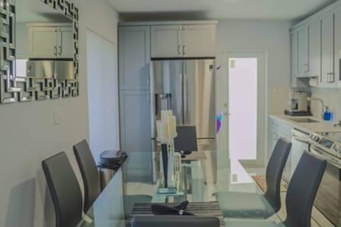 Sleek, modern kitchen with stainless steel appliances, ample cabinet space, and a glass dining table for six. Perfectly equipped for cooking and dining, offering a stylish and functional space for your stay. Ideal for comfort and convenience.