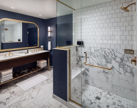 Large bathroom with walk-in shower with seat and two sinks.