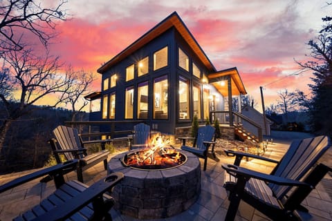 Stunning modern cabin exterior with a glowing fire pit and sunset views.