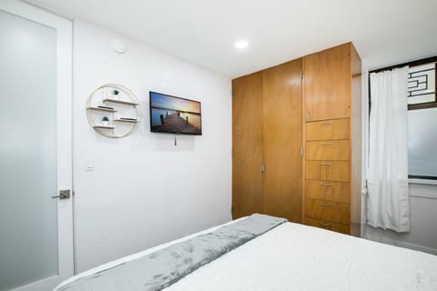 A serene and modern bedroom featuring a comfortable king-size bed with plush linens and accent pillows. The room includes stylish nightstands with matching lamps, a piece of tranquil artwork, and ample built-in wooden storage, creating a cozy and function