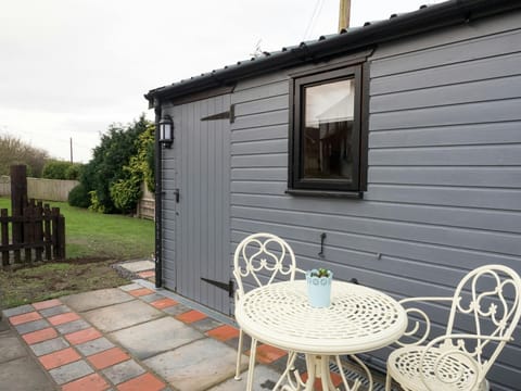 Outside view of Shepherds Rest with small patio area, round garden table and two chairs