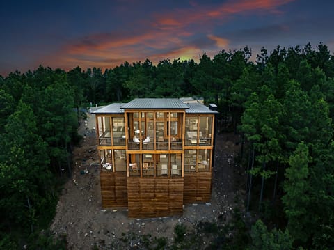 Two spacious back decks offer everything you need for outdoor living, including dining space, lounge chairs, a hot tub, barrel sauna, propane fireplaces, TVs, and cozy swing chairs—all surrounded by stunning mountain views.