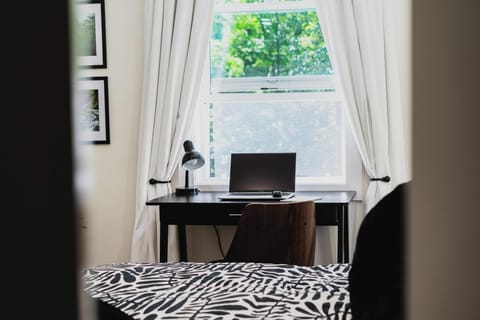 - Dedicated workspace with desk and chair for remote work  
- Bright natural light from large window for focus  
- Peaceful view creates a productive work environment  
