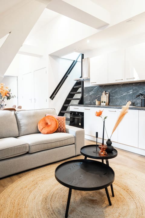 Two black, round mini center tables offer a convenient and stylish touch to the living space, perfectly positioned for easy access to the kitchen.