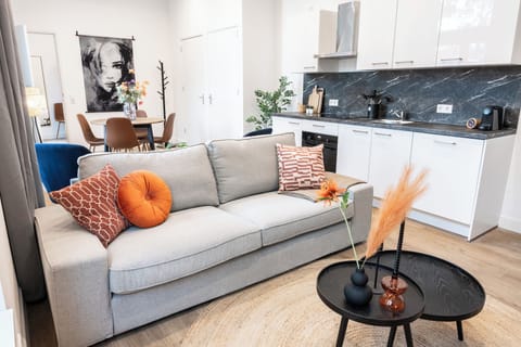 A welcoming and airy studio apartment Tilburg with large windows, a vibrant floral centerpiece, and a mix of modern and cozy seating for relaxation. Perfect for Bed en Koffie near Tilburg Centrum, and an affordable stay for Efteling or Safaripark Beeksebergen.