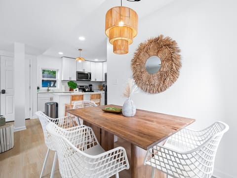 Modern dining nook with woven mirror and chic pendant light - Wooden table paired with stylish chairs for shared Airbnb meals - Bright setup perfect for casual dining and conversations